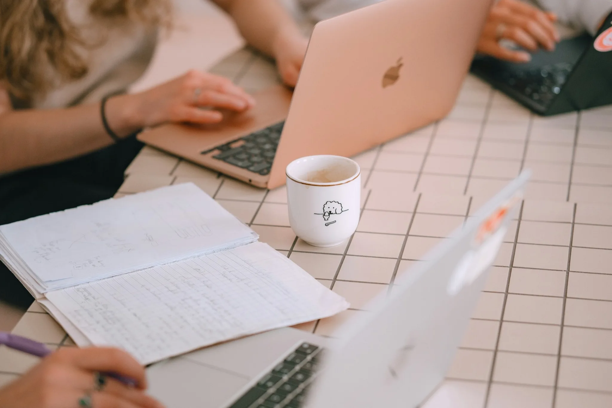 Hands, notebooks, and laptops arranged for a product strategy session.